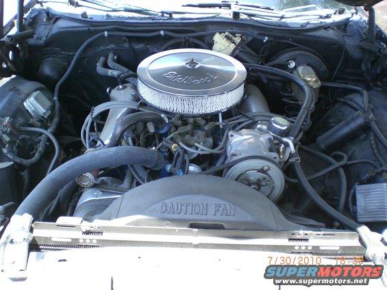 Engine bay with chrome air cleaner, V-belt driven accessories, and a black fan shroud with caution text