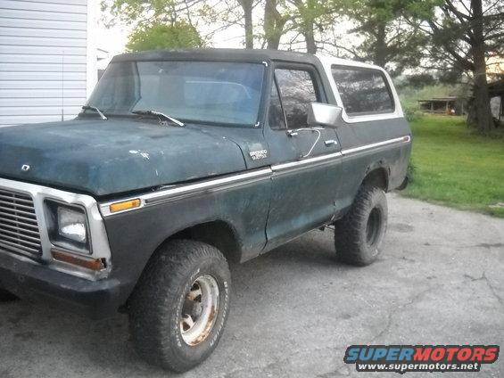 Dark green Ford Bronco with white top, lifted suspension, and off-road tires parked on concrete