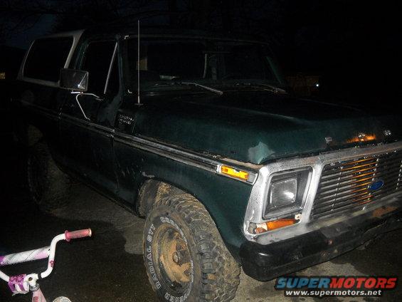 Green Ford Bronco with white top, front quarter view. Has a chrome grille and square headlights