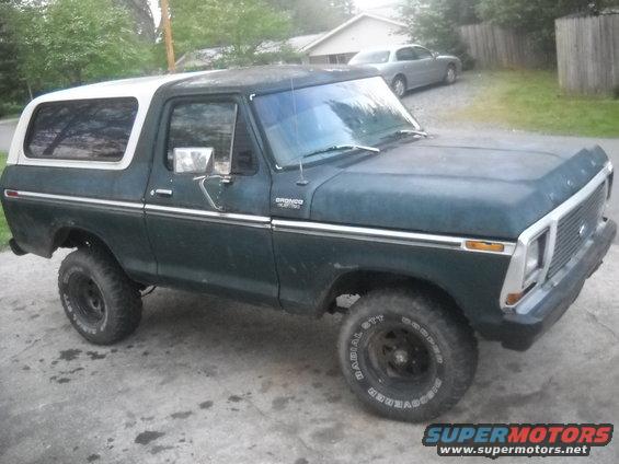 Dark green Ford Bronco with white removable top, lifted suspension, and off-road tires