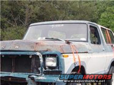 Ford Bronco with rusty hood and front damage, orange straps on hood