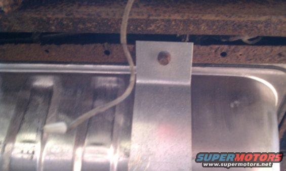 Underbody view of a vehicle showing a fuel tank and rusted frame