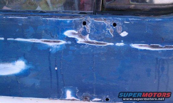 Close-up of blue vehicle body with rust and primer spots