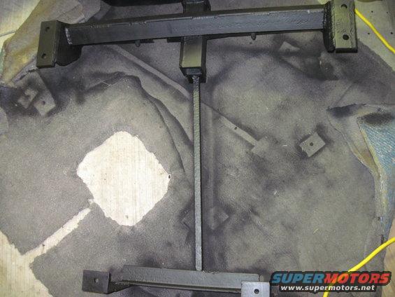 Painted metal frame with mounting brackets, laid on a floor with dark stains