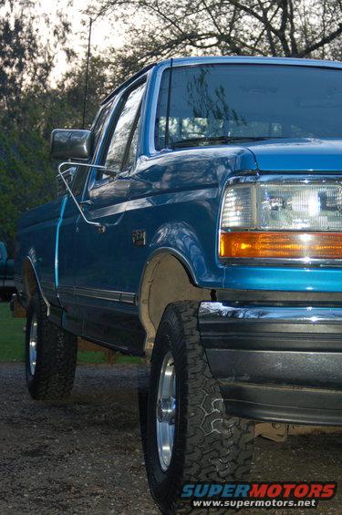 Blue pickup truck parked on gravel, side view showing front fender and door