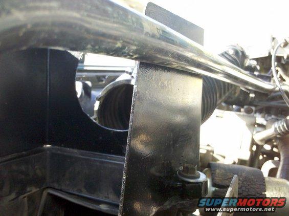 Close-up of black plastic housing and metal bracket in a vehicle's engine bay