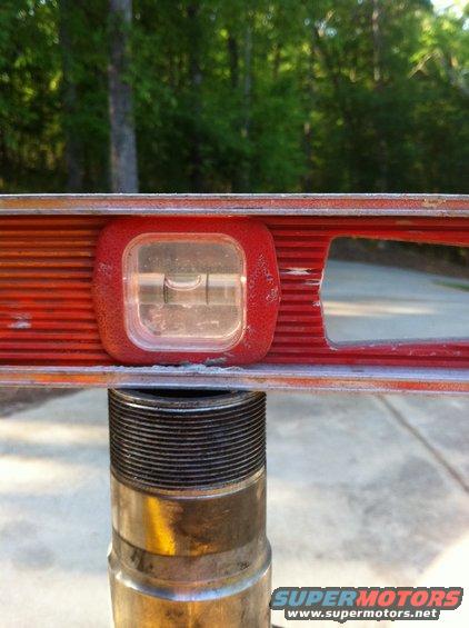 Red level tool with bubble centered over a metal threaded shaft