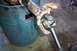 1988 Ford Bronco - A driveshaft U-joint is held up, with a blue barrel in the background.