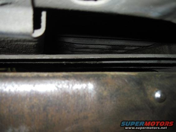 Close-up of layered metal parts underneath a vehicle, possibly frame rails