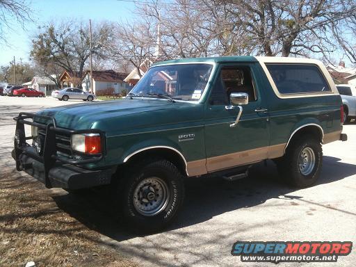 Green Ford Bronco with tan lower trim and a brush guard on the front