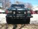 1989 Ford Bronco - Front view of a green Ford Bronco with a black brush guard and two round fog lights.