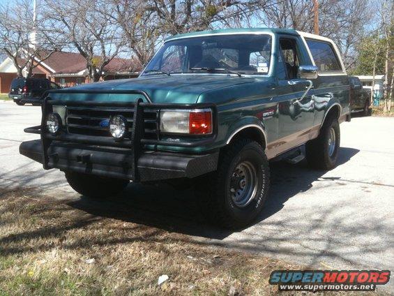 Green 1987 Ford Bronco with a brush guard and tan lower body trim