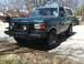 1989 Ford Bronco - A green 1987 Ford Bronco with a brush guard is parked on a street.