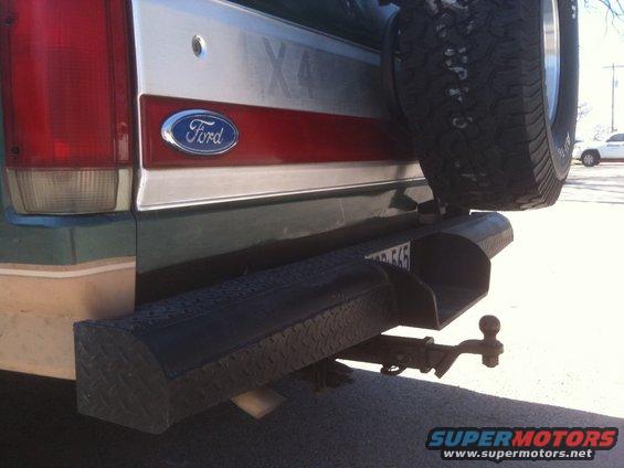 Green Ford Bronco rear bumper with spare tire mounted, tow hitch, and license plate
