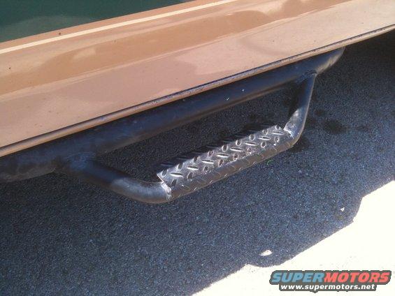 Tan and green vehicle side step with diamond plate tread, close-up