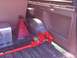 1989 Ford Bronco - The interior cargo area of a vehicle contains a red hi-lift jack, a red jack stand, and a diamond plate toolbox.