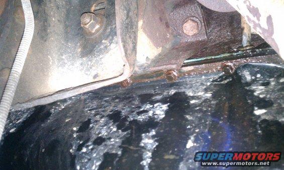 Underside of a vehicle with visible rust and oil stains