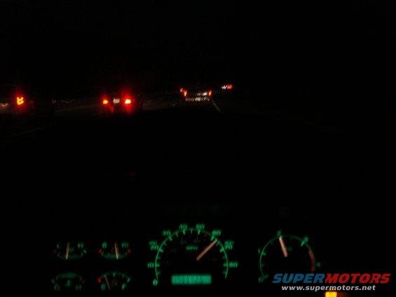 1989 Ford F-250 interior dashboard with glowing green gauges and taillights of cars ahead