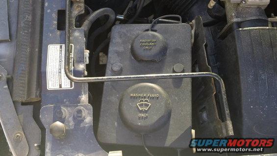 Engine bay with radiator coolant and washer fluid reservoirs. Blue paint visible