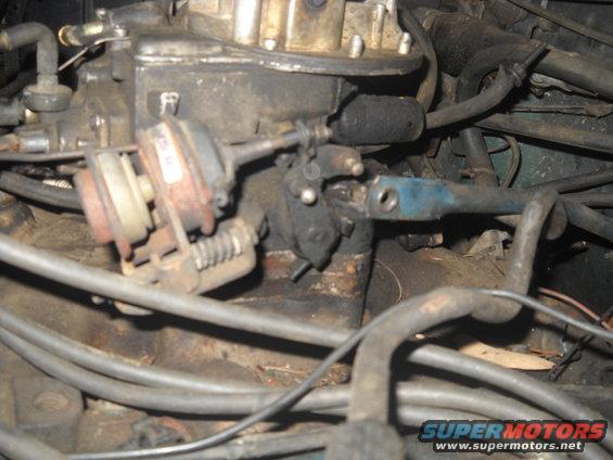 Engine carburetor with vacuum lines and linkage, showing rust and grime