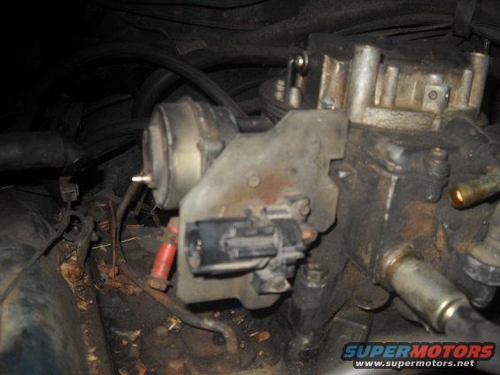 Close-up of carburetor and engine components with visible wiring and hoses