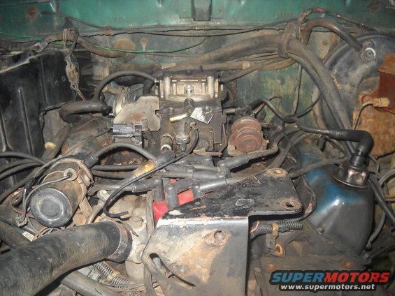Engine bay showing a carburetor, distributor, and various hoses and wires
