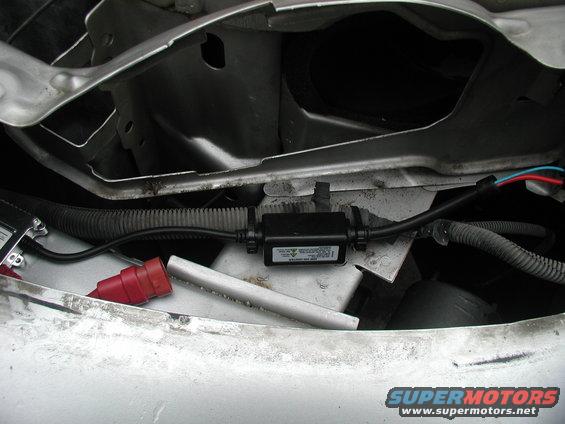 HID ballast with wiring harness and red connector, mounted in vehicle engine bay