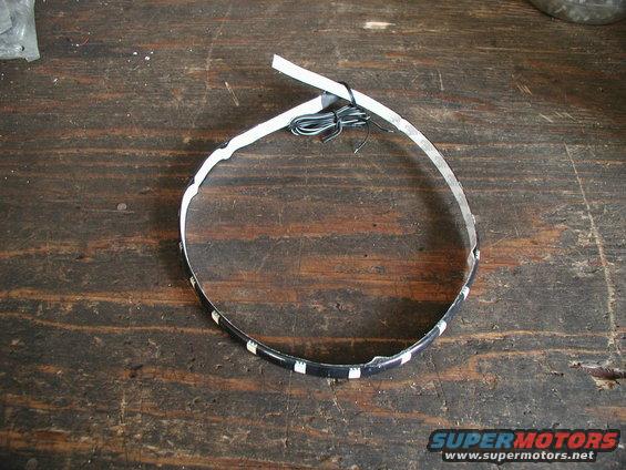 LED strip light with wires, lying on a wooden surface. Supermotors.net logo visible