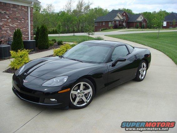 Black 2006 Chevrolet Corvette parked on a concrete driveway in front of a brick house