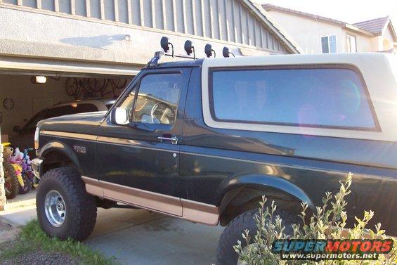Dark green Ford Bronco parked in driveway, light bar on roof
