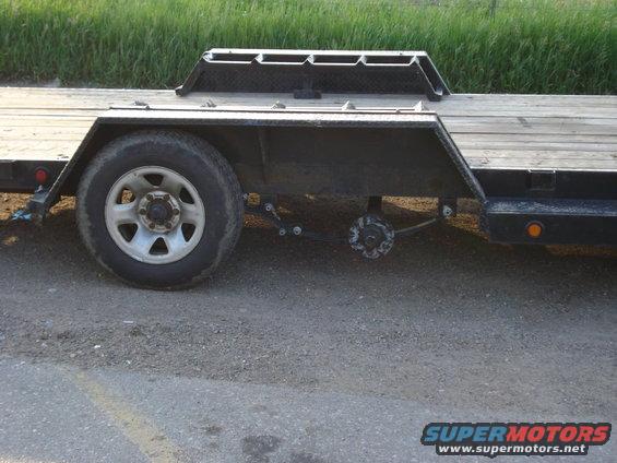 Trailer axle with one wheel visible, showing suspension and brake drum