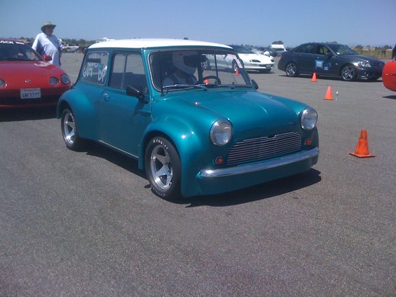 Teal classic Mini Cooper with white roof and racing wheels, 3/4 front view