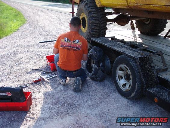 Yellow truck on trailer, man working on tire