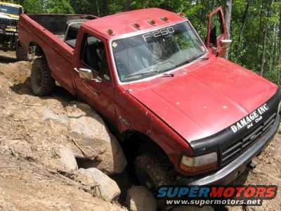 Red Ford F-250 pickup truck with "F250" on windshield, navigating rocks. Another yellow vehicle is partially visible