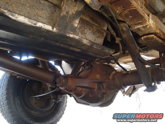 Underside view of a rusty truck's rear axle and driveshaft