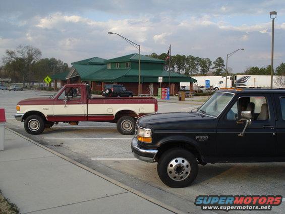 1989 Ford F-250 crew cab pickup truck, black, 3q-front view. Another red and white pickup is parked behind