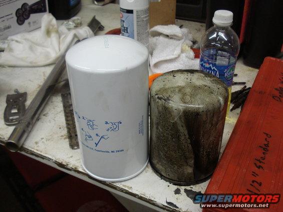 New white oil filter next to a used, dirty oil filter on a workbench