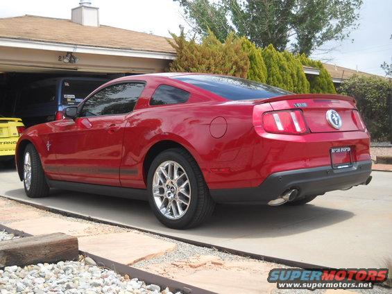 Red Ford Mustang coupe parked in driveway, yellow vehicle partially visible behind it