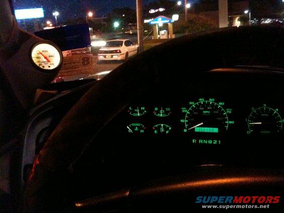 Interior view of a dashboard with illuminated gauges and a digital odometer reading 055575