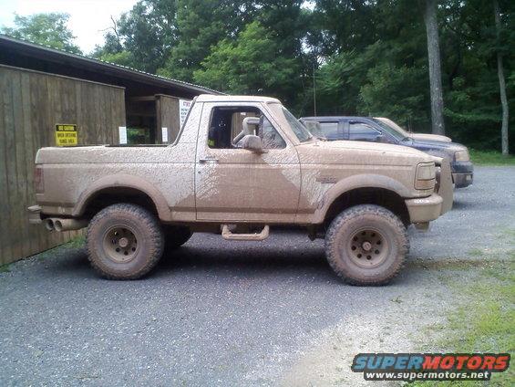 Mud-covered 1996 Ford Bronco, side view, parked next to another vehicle
