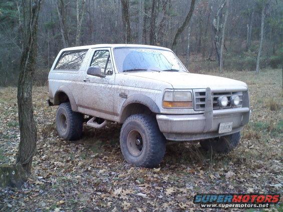 1996 Ford Bronco parked in a wooded area with fallen leaves on the ground