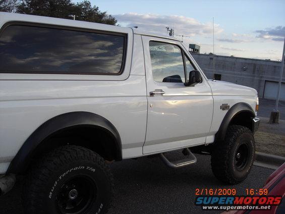 White 1996 Ford Bronco parked outside, side view. Mud-terrain tires visible