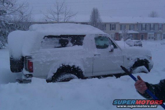 white SUV buried in snow, with another vehicle visible in the background