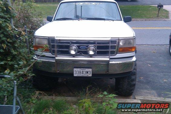 White Ford F-150 truck with a chrome bull bar and fog lights. License plate reads 33843M3