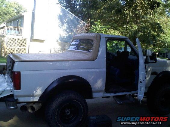 1996 Ford Bronco with soft top, driver's door open, parked outside