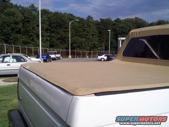 1996 Ford Bronco with tan soft top, rear view. Other cars parked in background
