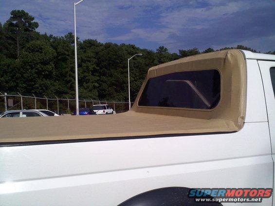 White Ford Bronco with a tan soft top, parked near other cars