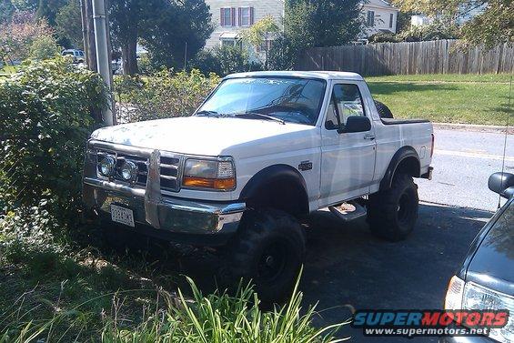 Lifted white Ford Bronco parked on a driveway, front end visible