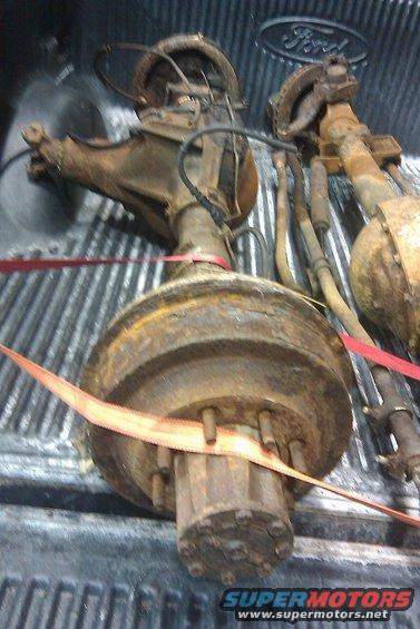 Two rusty Ford rear axles in a truck bed. Ford logo visible