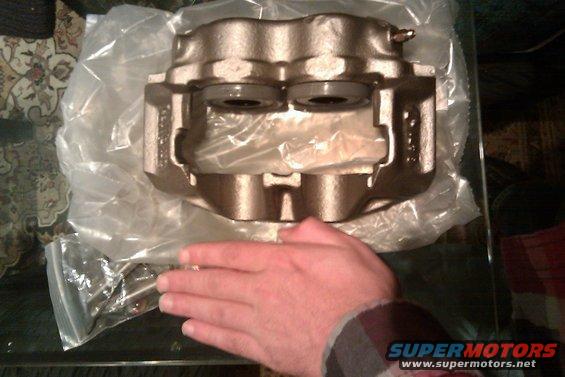 Bronze brake caliper in plastic packaging, held by a hand